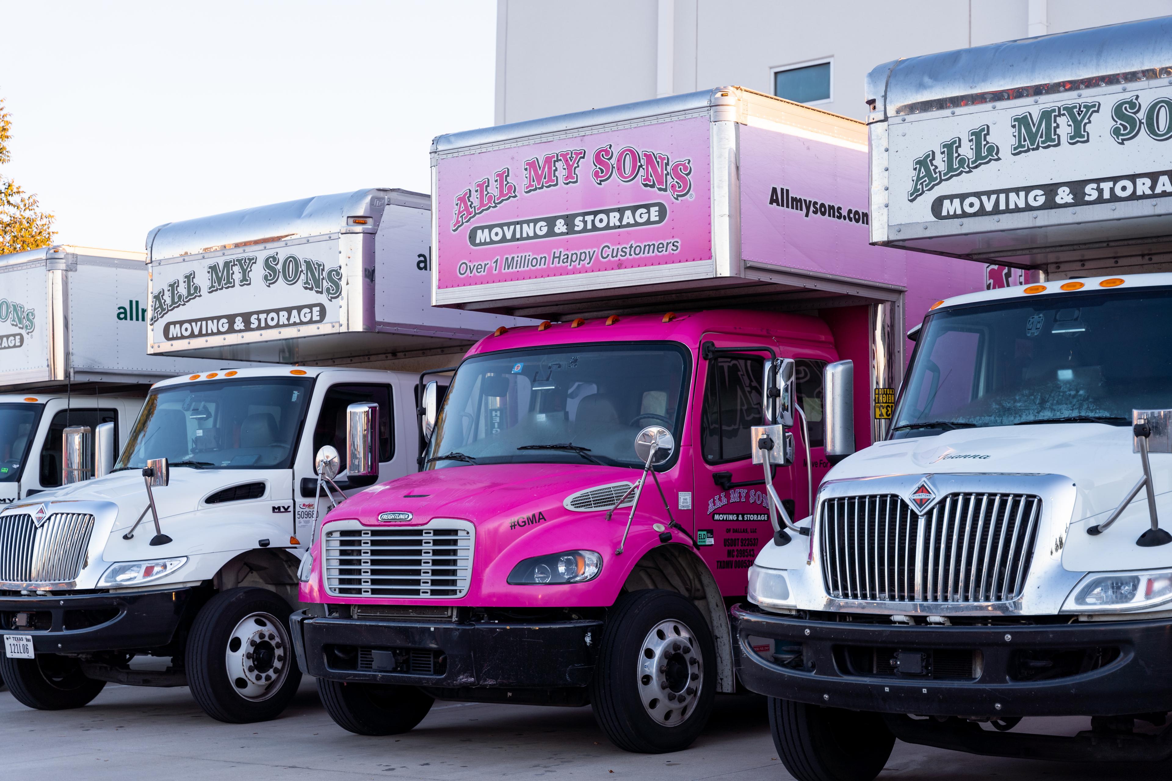 Special All My Sons Pink Race for the Cure truck parked between normal moving trucks.